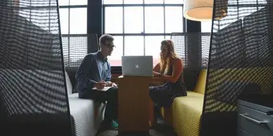 Two adults talking over a laptop page